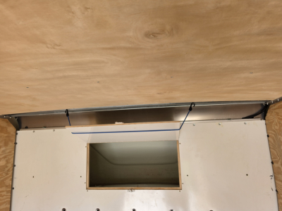 Truck cargo area showing a rectangular cutout in white paneling with wood backdrop
