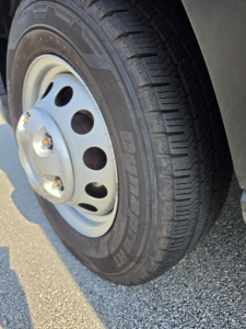 Wheel and tire on a Ford Transit 350 HD showing Hankook Dynapro HT tire with steel wheel and lug nuts.
