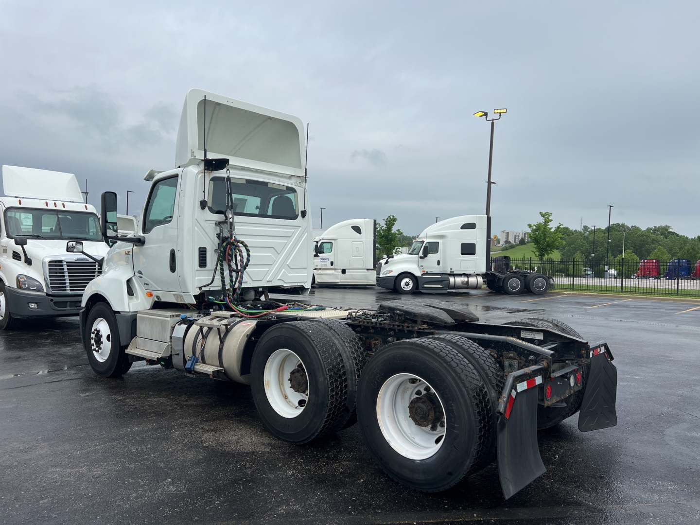 Truck chassis with cab raised showing LT tractor sleeper area and dual rear axles; no clear legible text visible on components.