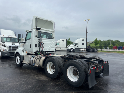 Truck chassis with cab raised showing LT tractor sleeper area and dual rear axles; no clear legible text visible on components.