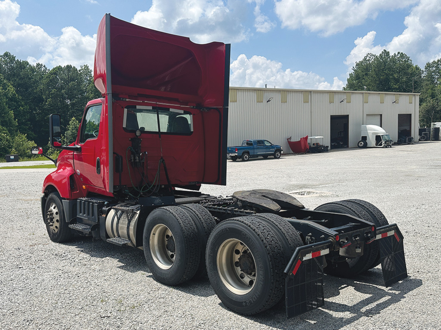 Truck: 2021 International LT625 daycab, red cab raised, showing rear chassis with dual rear axles and fifth wheel, stock number 553730 visible in lot.