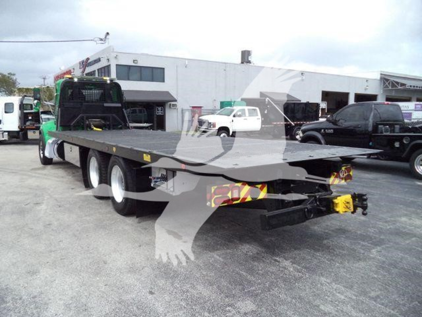 Peterbilt 348 rollback trailer with long flatbed and multiple axles, rear view showing hitch and warning triangles.