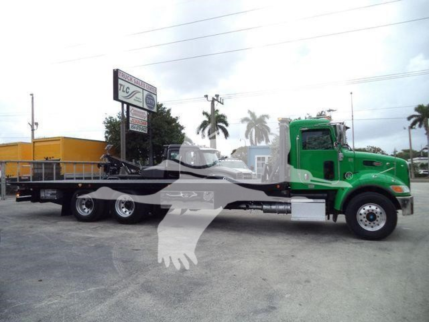 2018 Peterbilt 348 rollback truck with green cab and long flatbed trailer, side view showing dual rear axles and chrome exhausts.