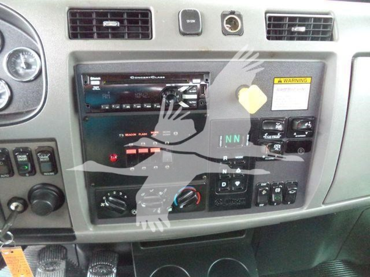 Peterbilt 348 dashboard/console showing stereo head unit, control switches, and warning sticker.