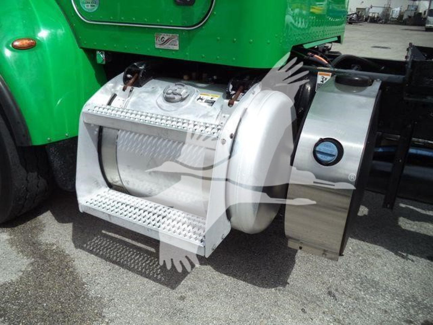 Side view of a green Peterbilt 348 with a chrome fuel tank/step and access panels; visible labels and caps on the fuel tank area.