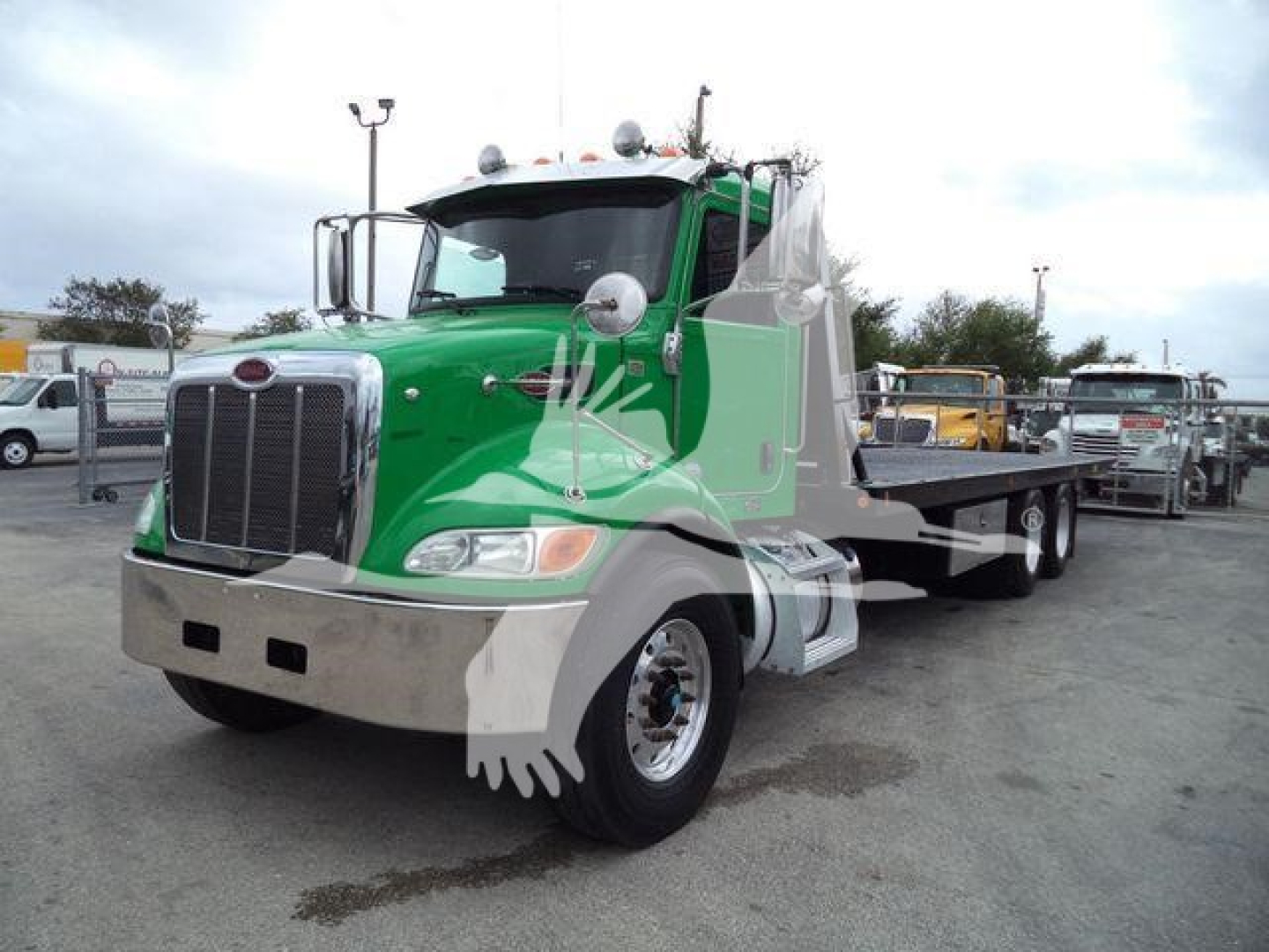 Peterbilt 348 rollback truck in green and silver, front three-quarter view, with chrome bumper and large grille, stock number T67153FM.