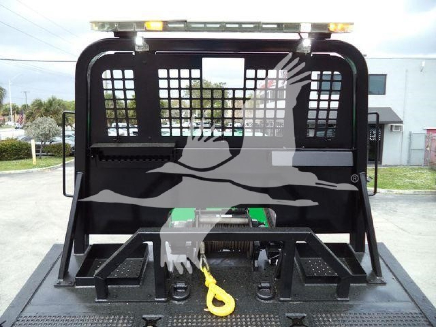 Peterbilt 348 rollback truck bed with cage and hitch, rear view showing towing eye and tool boxes.