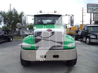 Front view of a green and white 2018 Peterbilt 348 rollback truck with chrome bumper and grille, stock number visible in background.