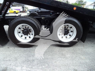 Peterbilt 348 rollback truck rear dual wheels showing steel rims and tires with hydraulic lines and undercarriage components.