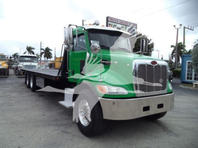 Peterbilt 348 rollback tow truck in green and black with chrome grille and front bumper, side view showing flatbed and dual fuel tanks.