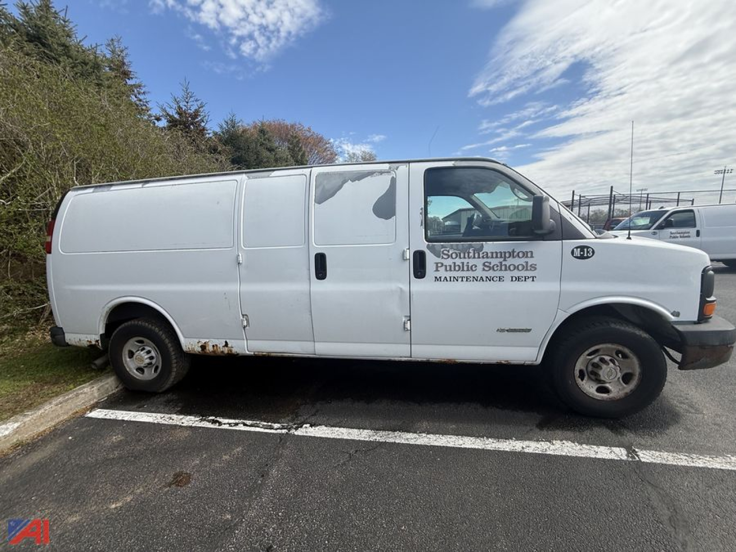 Side view of a white 2005 Chevrolet Express 3500 cargo van with maintenance department lettering on the front door and some rust along the lower body.