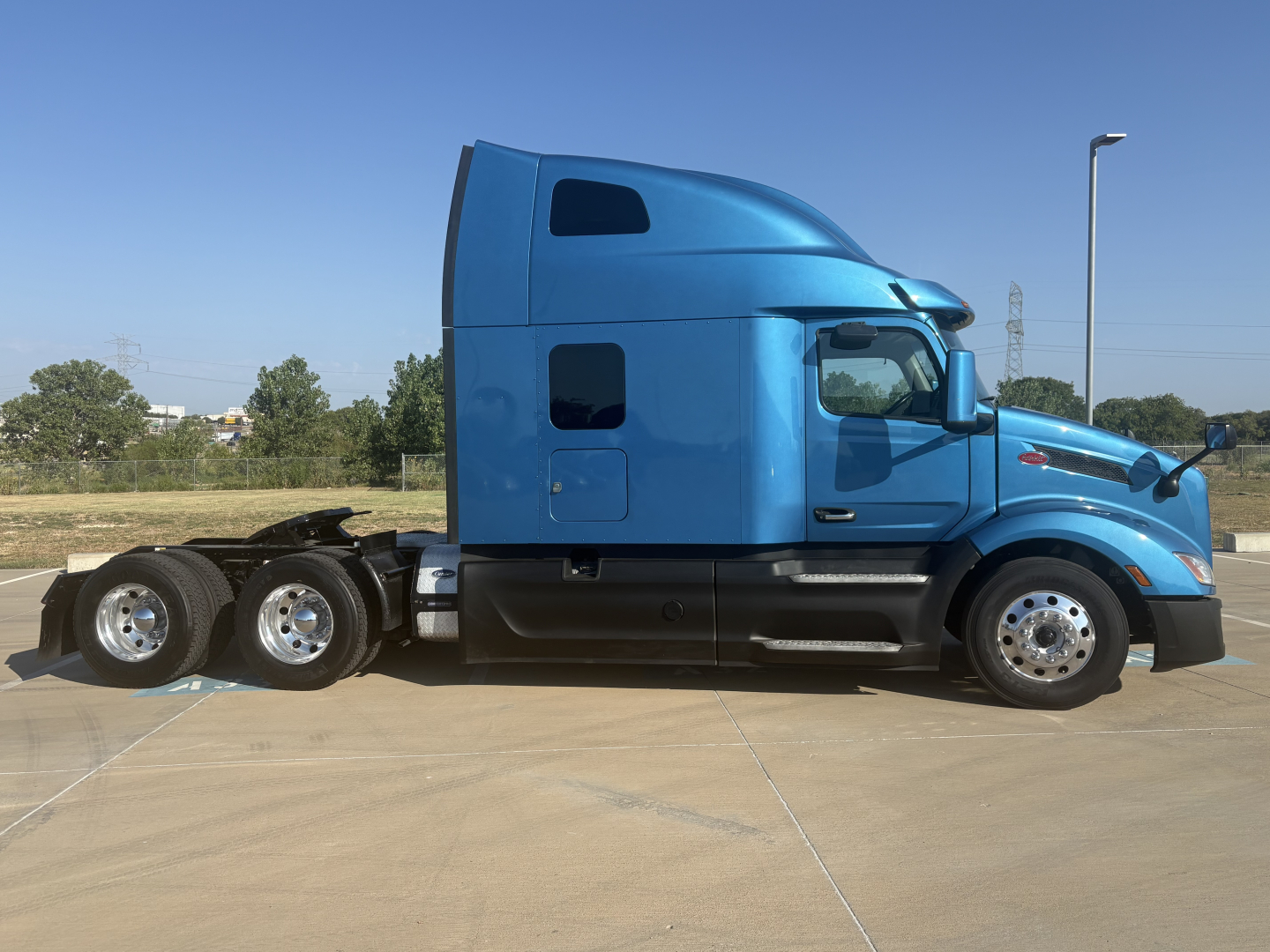 Peterbilt 579 sleeper cab tractor in blue, side view showing cab with aerodynamic roof fairing and dual rear axles.