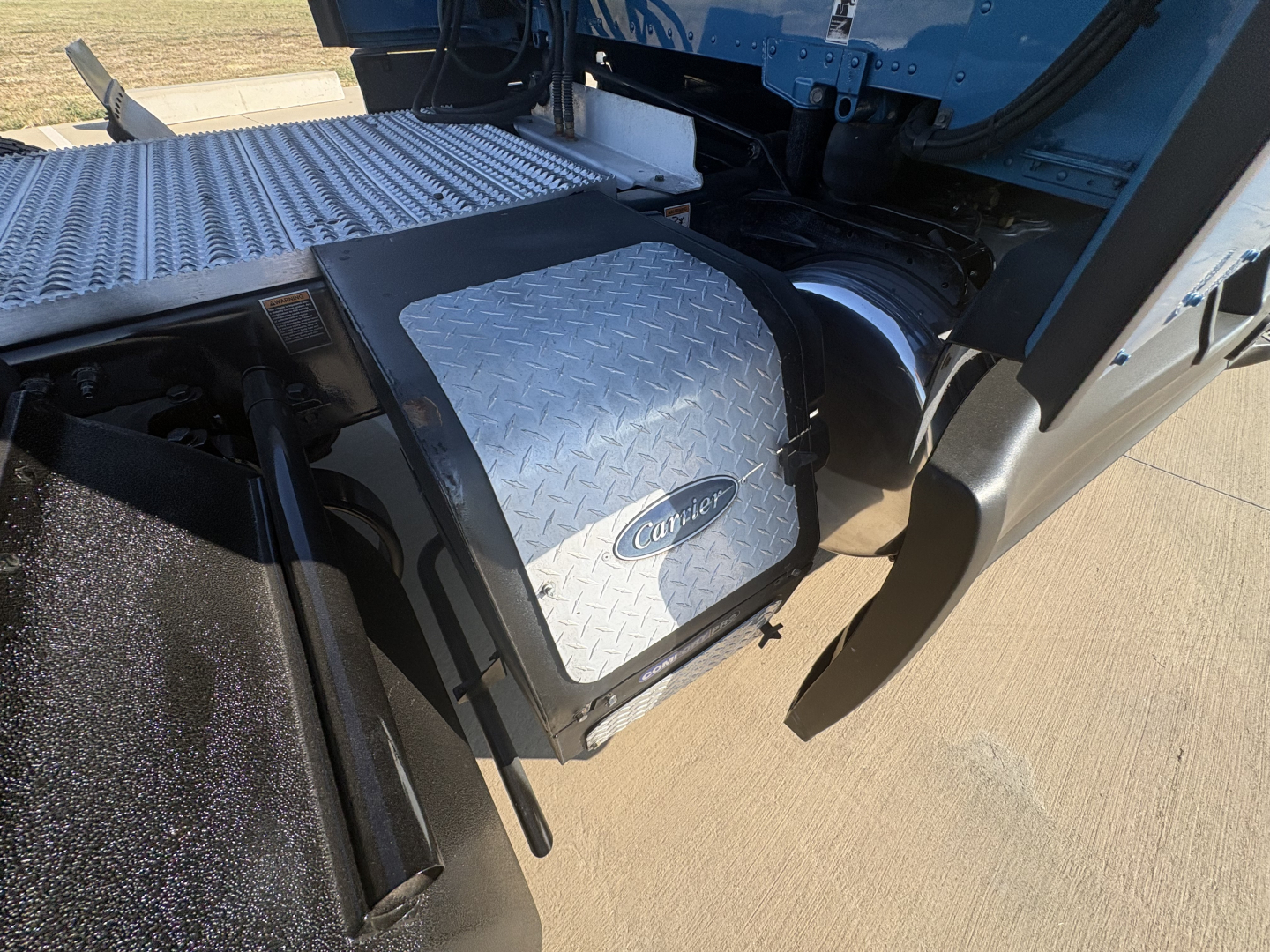Peterbilt 579 truck side step with aluminum diamond plate toolbox and step; visible drive line area and fender, undercarriage components.