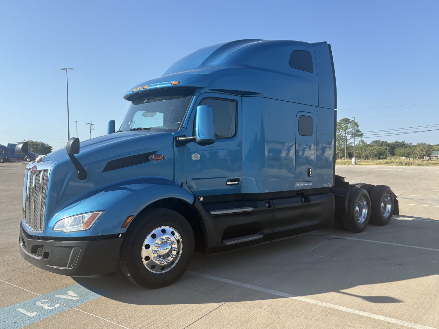 Peterbilt 579 semi-truck in blue from front-left view, with sleeper cab, chrome wheels, and dual rear axles.