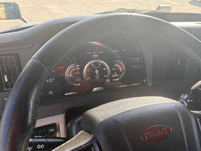 Peterbilt 579 dashboard view with steering wheel showing gauges and digital display, inside cab.