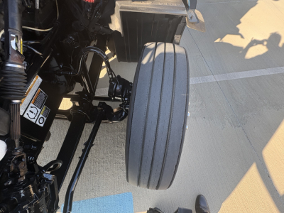 Front wheel area of a 2022 Peterbilt 579 truck showing dual rear tires and suspension components.