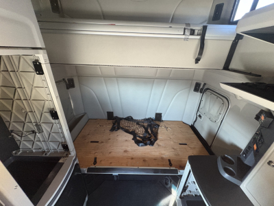 Truck interior cargo area of a Peterbilt 579 sleeper cab with wooden deck in rear, cargo tie-downs, and side panels.