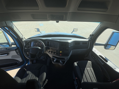 Peterbilt 579 interior dashboard view from driver seat showing steering wheel, instrument cluster, center console, and driver and passenger seats.
