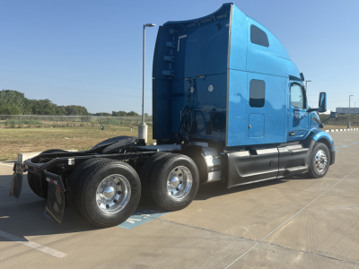 Blue 2022 Peterbilt 579 tractor cab, side view showing sleeper, rear wheels, and exposed chassis.