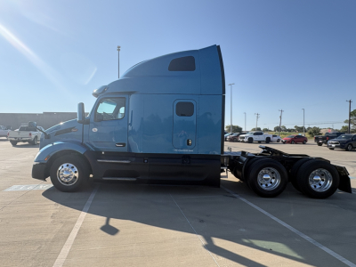 Peterbilt 579 tractor-trailer in blue, side view showing sleeper cab and dual rear axles.