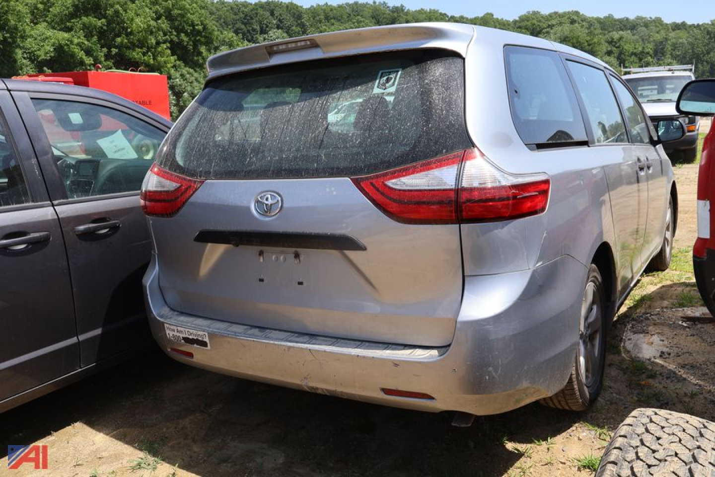 Rear view of a silver 2016 Toyota Sienna minivan showing taillights and rear bumper in a used car lot.