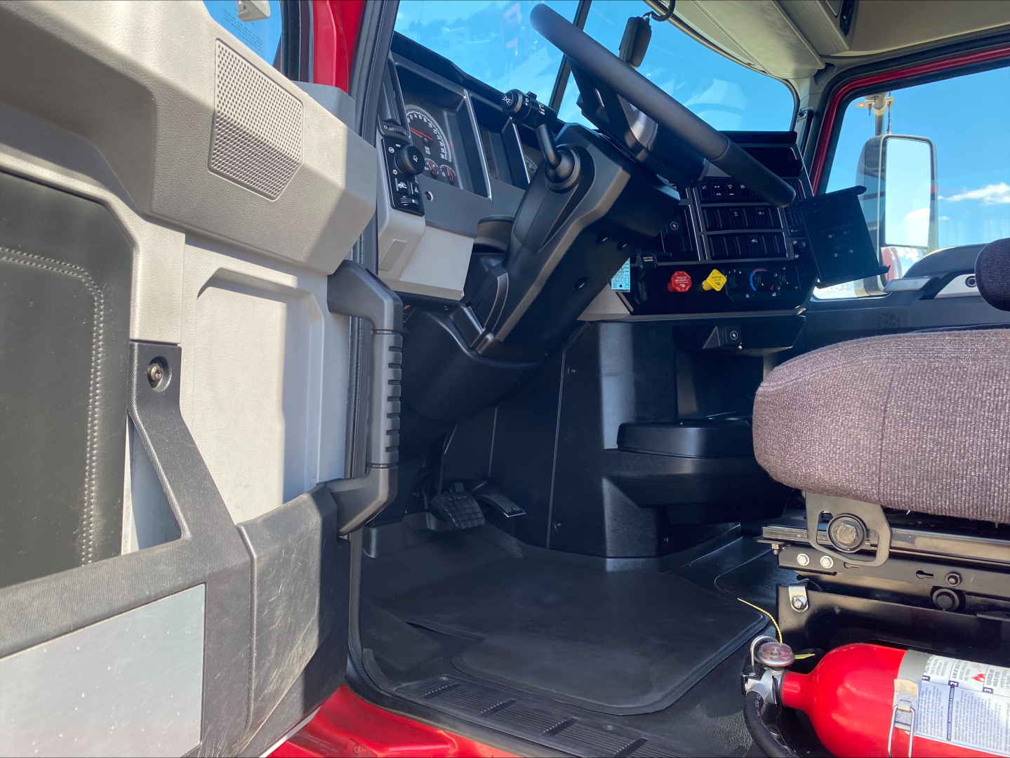 Truck cab interior of a 2020 Mack AN64T70 showing dash, steering wheel, driver seat, and floor area inside the sleeper model.