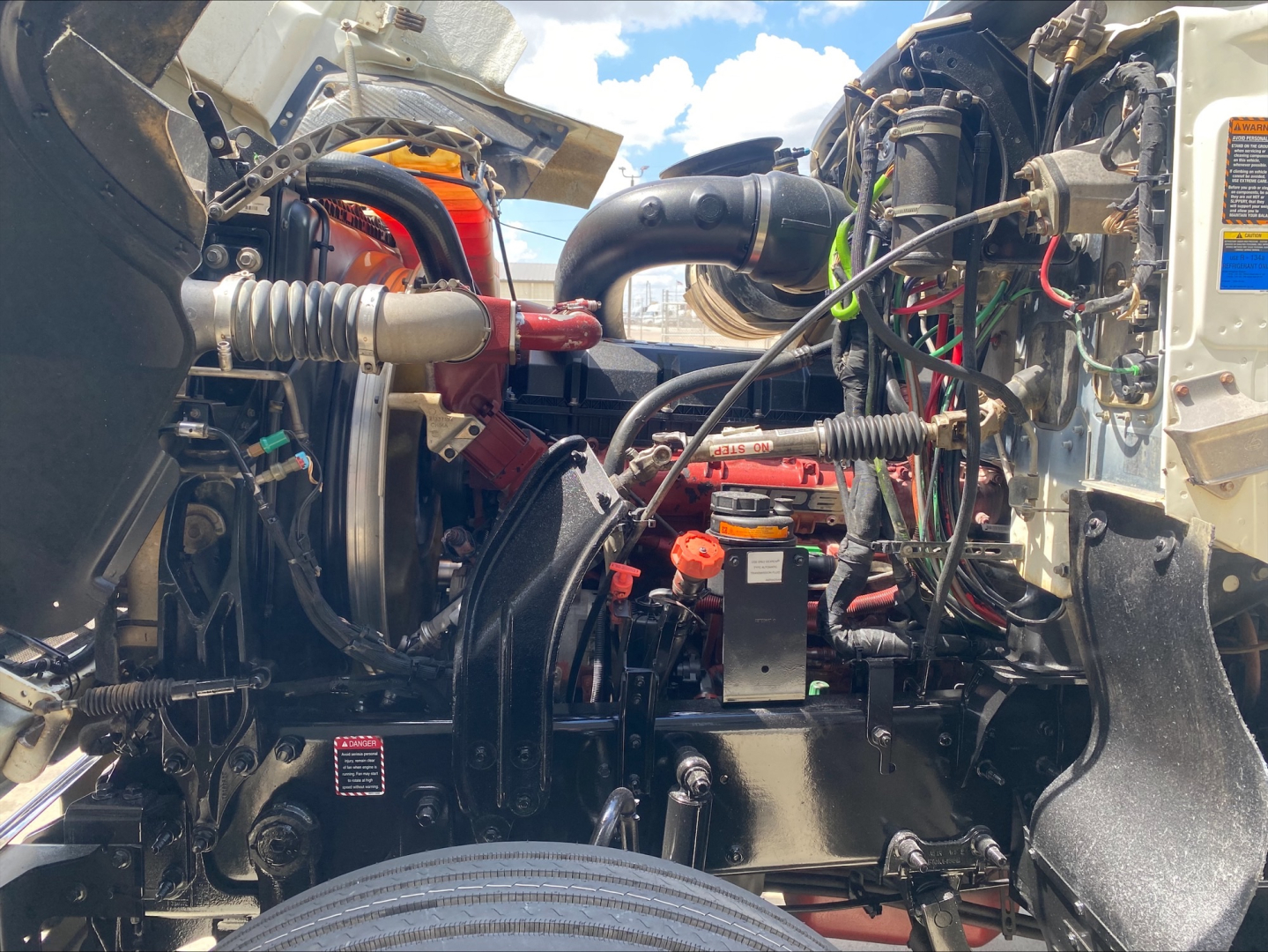 Front engine bay of a 2020 Mack AN64T70 showing engine components, hoses, wiring, and air intake; visible labels and electrical connections.