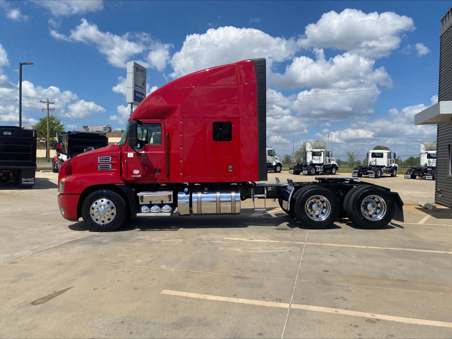 Side view of a red 2020 Mack AN64T70 conventional sleeper truck with single cab and dual rear axles, chrome fuel tanks, and clear sky.