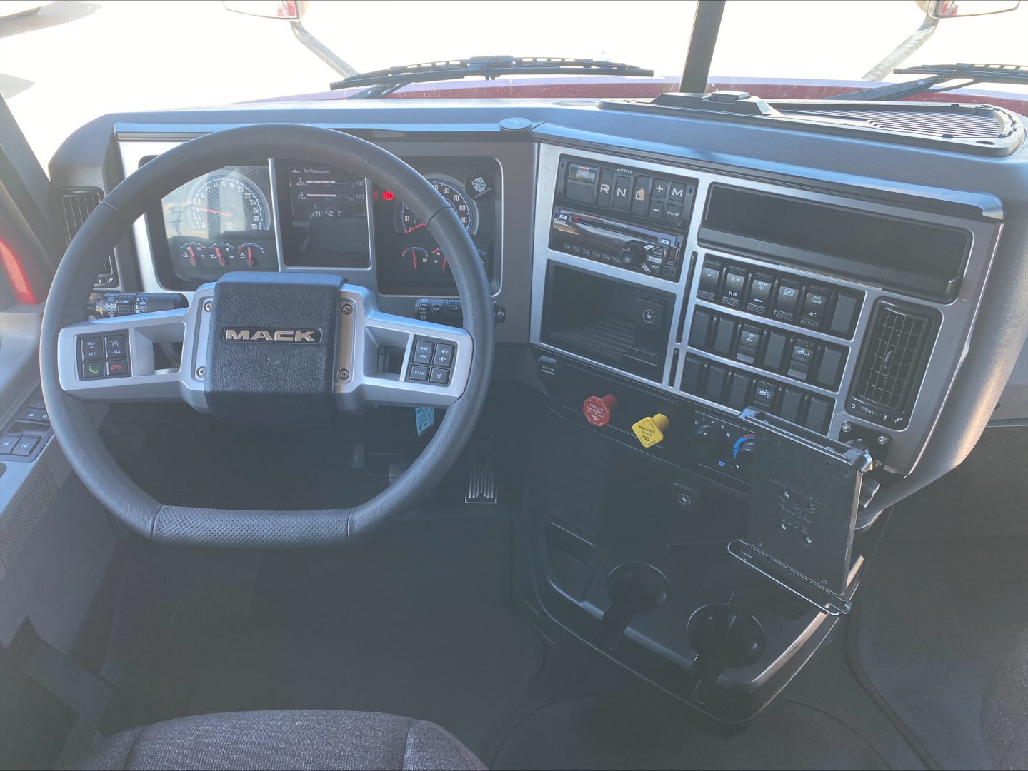 Mack AN64T70 truck interior showing steering wheel, instrument cluster, and dashboard controls with gear shifter and switches.
