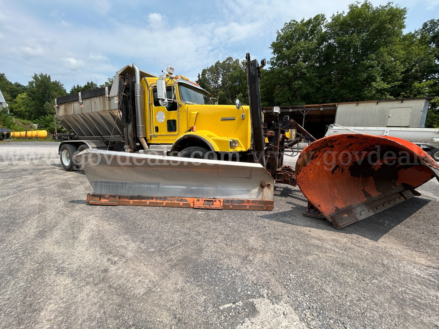 Kenworth T800 plow truck in yard with front-mounted bulldozer-style blade and orange snow plow, yellow cab, stock number 3691-17 visible.