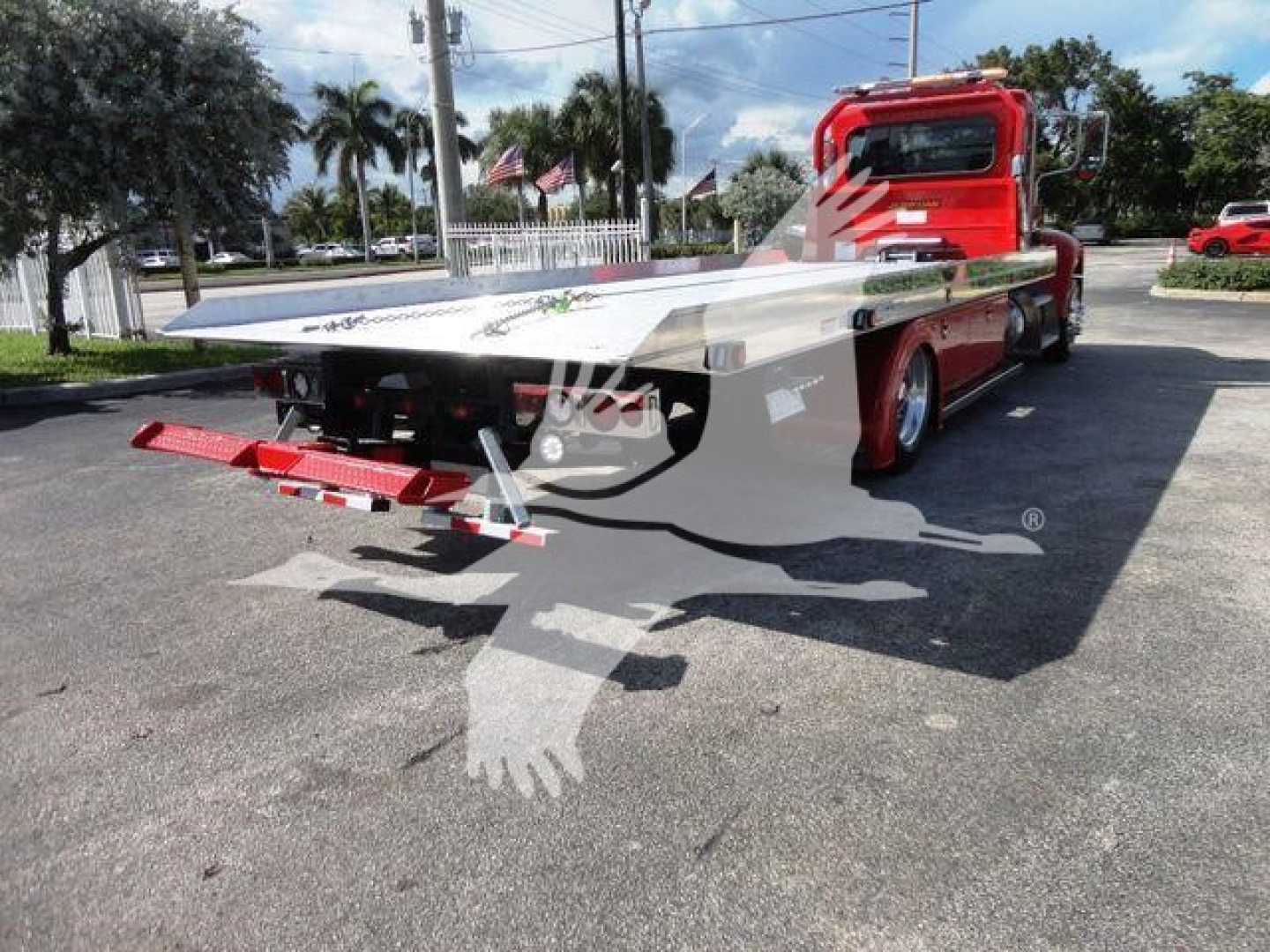 Peterbilt 337 rollback wrecker flatbed tow truck showing rear platform and red cab, decals and chain hooks visible.