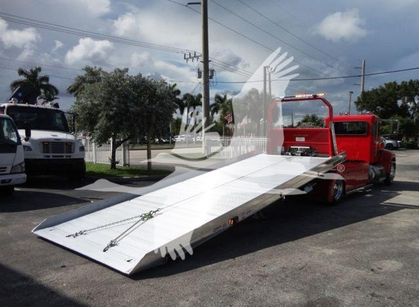 Peterbilt 337 rollback tow truck with a lowered aluminum ramp bed, red cab, side view showing VIN and stock details in listing.