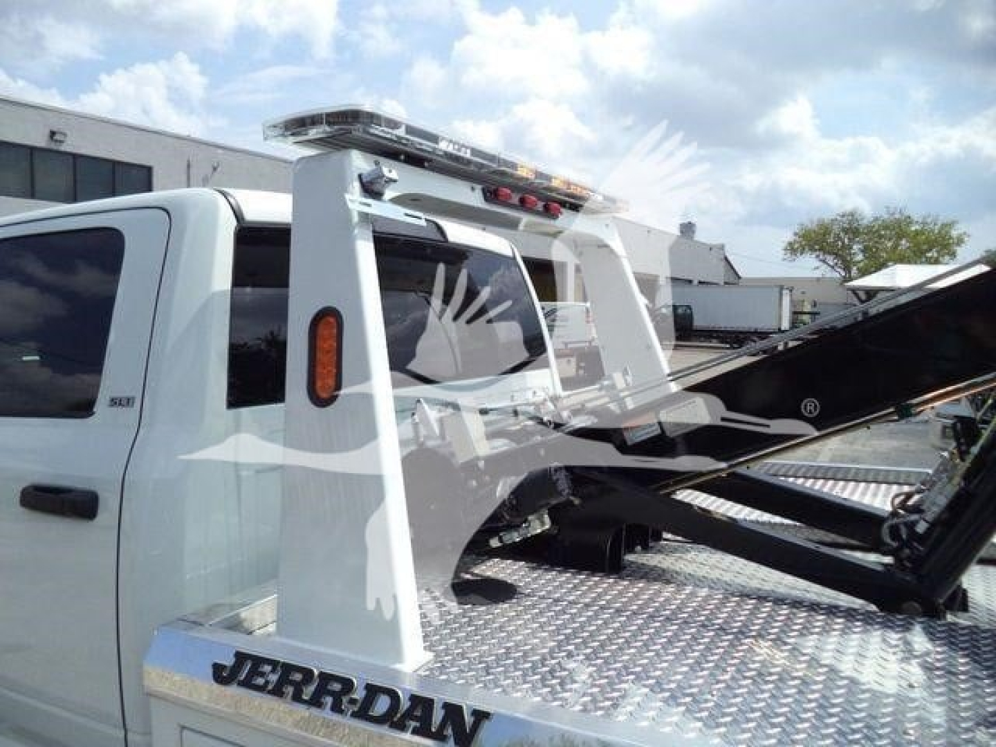 Truck bed with winch equipment on a white 2024 Ram 5500 SLT, tail area showing hydraulic tow hoist and diamond plate steel surface.