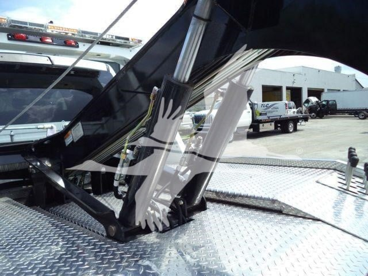 Ram 5500 SLT winch-equipped bed with hydraulic hoist and metal diamond plate surface showing winch components and hydraulic oil lines.