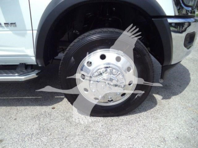 Truck wheel and tire close-up showing polished hubcap and tire treads on a Ram 5500 SLT front wheel; partial fender and running board visible.