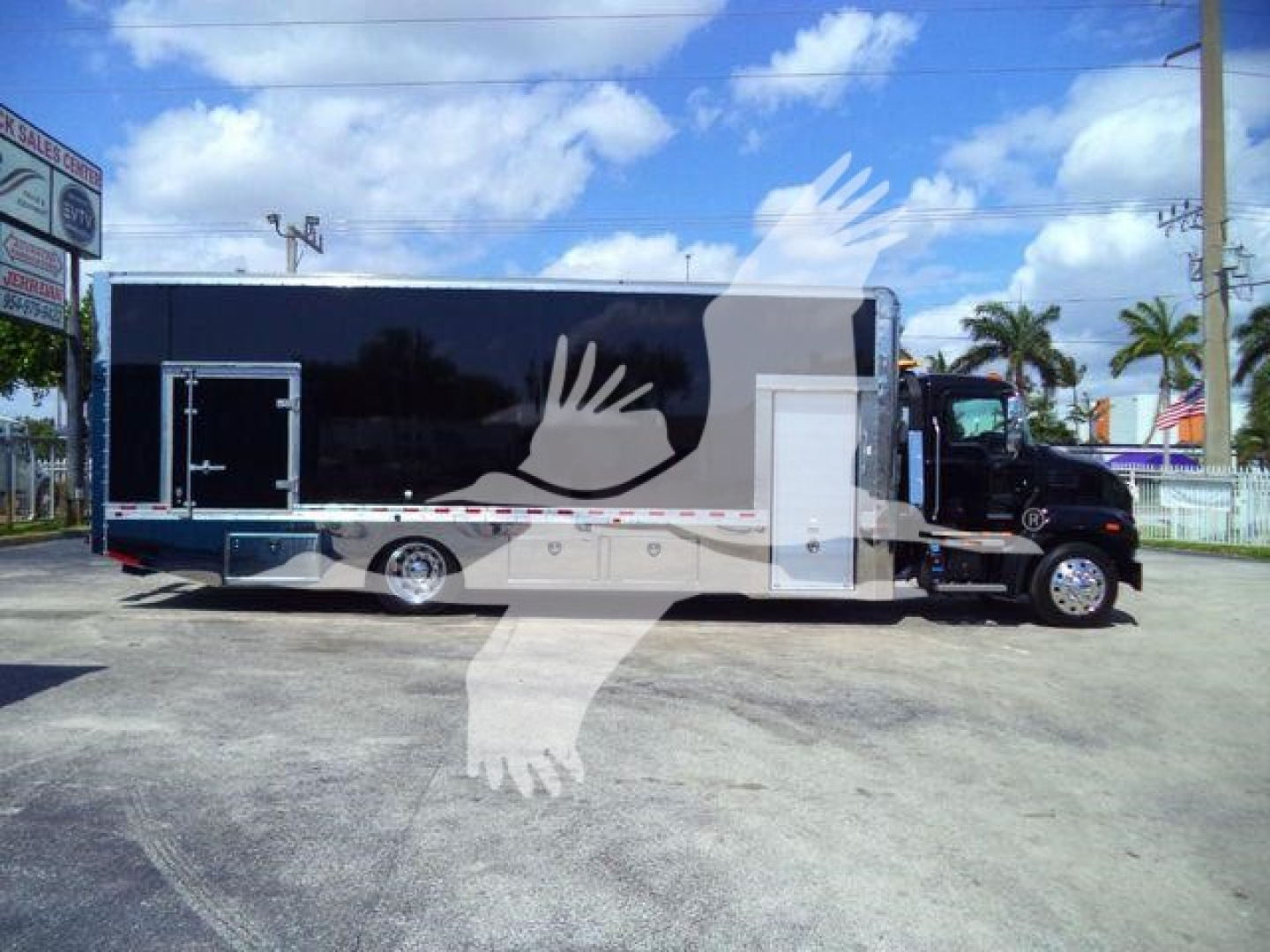 MD6 rollback truck body showing long black cargo trailer with white side door and rear access, mounted on a black truck chassis.