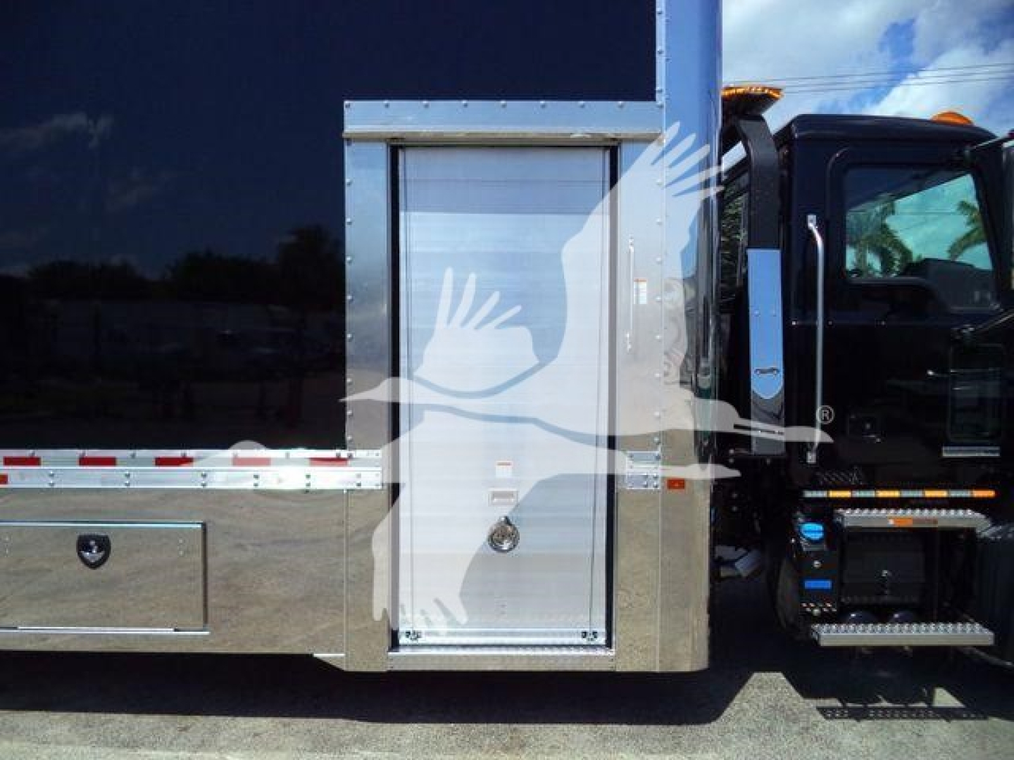 Truck side showing utility compartment door with polished metal panel and steps, part of a Mack MD6 rollback trucks chassis.
