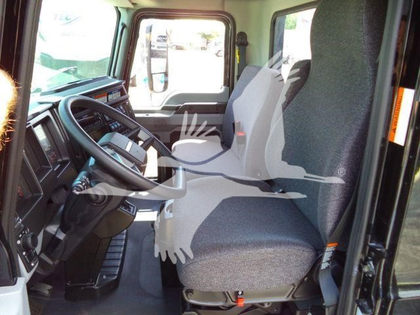 Mack MD6 truck cab interior showing driver seat and dashboard with steering wheel and console, view from open door.