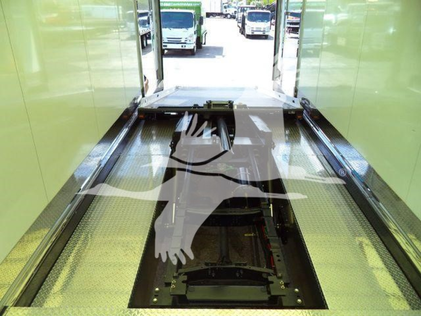 MD6 truck inside a green rollback bay, viewing the chassis/drive area with open floor pit for wheel lift.