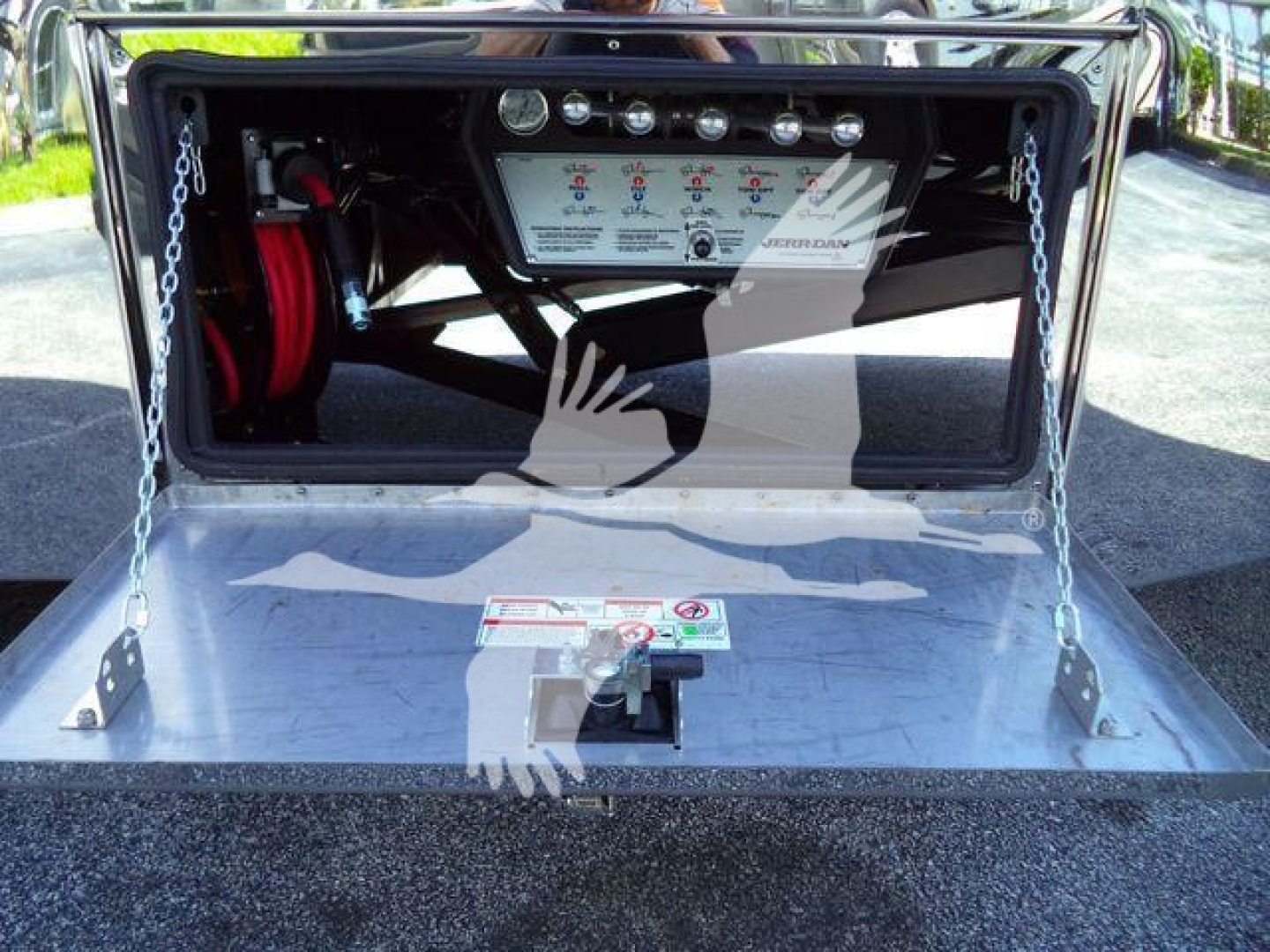Truck bed with hydraulic controls panel and storage box showing control levers and gauges in a Mack MD6 rollback unit.