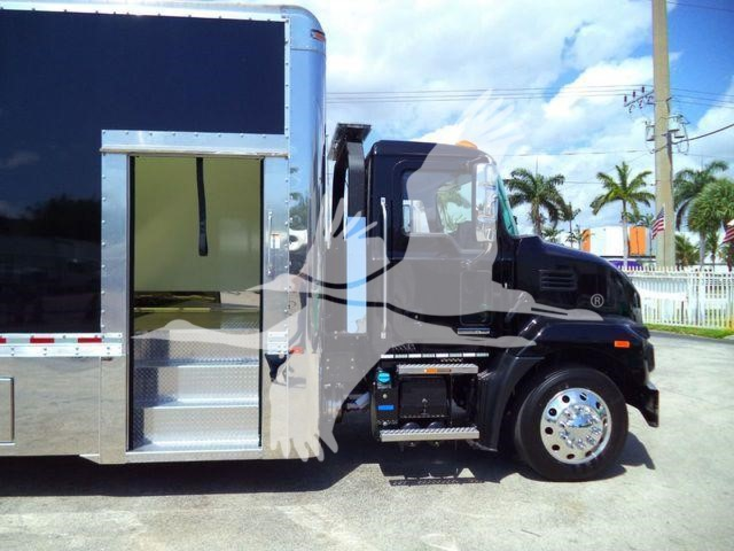 MD6 front/side view showing a Mack MD6 rollback truck with a large black cab, chrome wheel, and a metal utility area; no legible sticker text visible in the image.