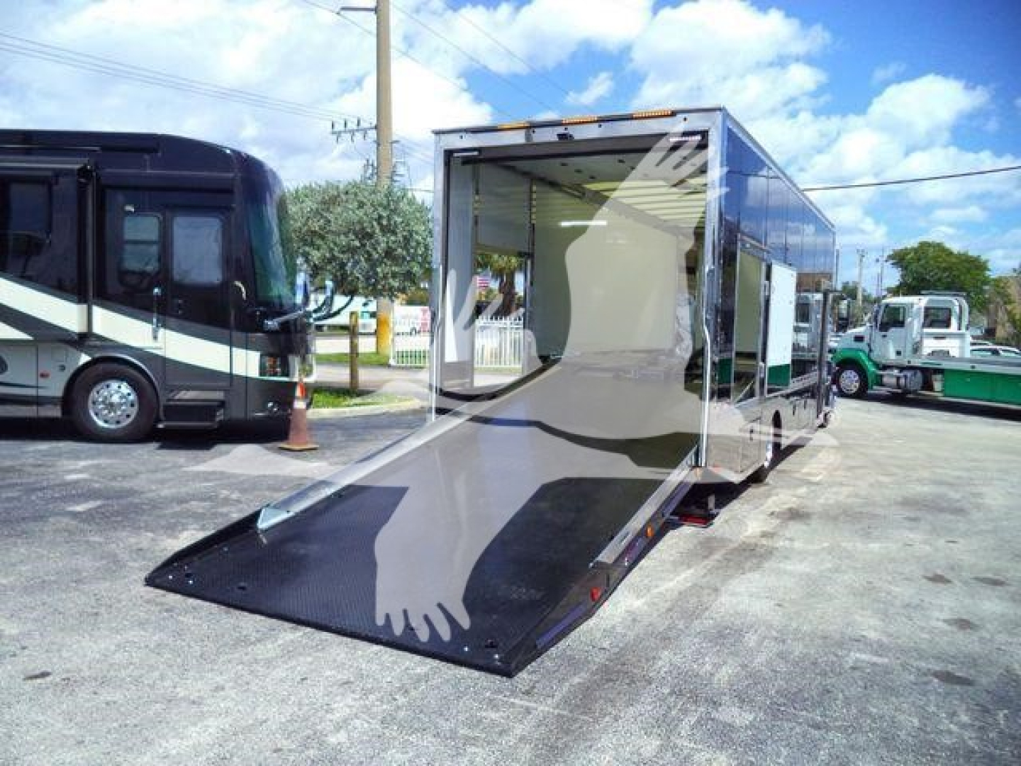MD6 loader/landscaping-style rollback truck with a lowered ramp in a parking lot, showing the interior cargo area of a 2026 Mack MD6 roll-off truck with a open rear and ramp extended.