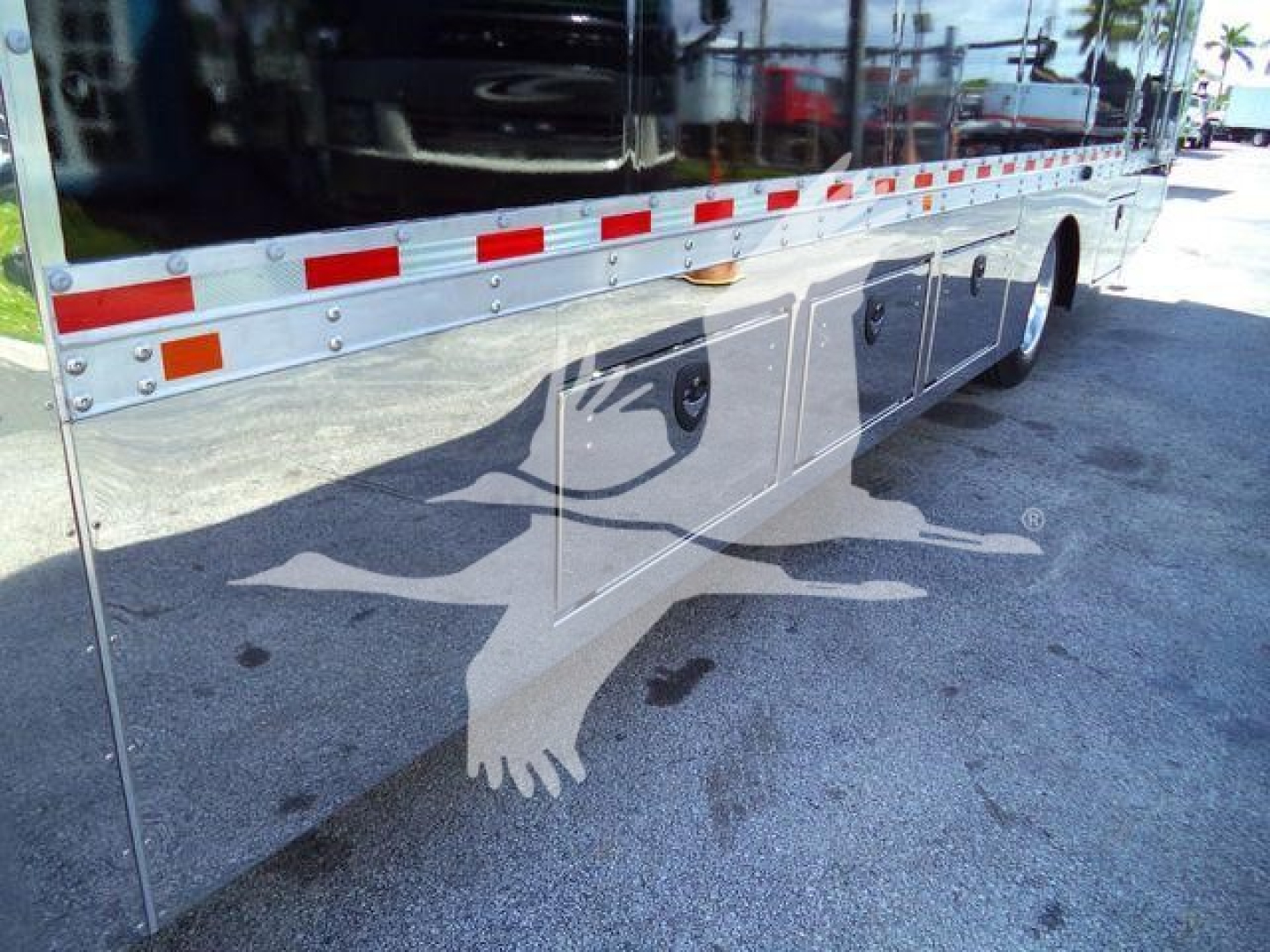 Mack MD6 rollback truck exterior side showing storage compartments and reflective decals along lower body.