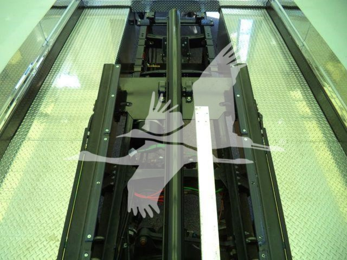 MD6 truck chassis and lift mechanism in an inspection bay showing metal rails and hydraulic components.