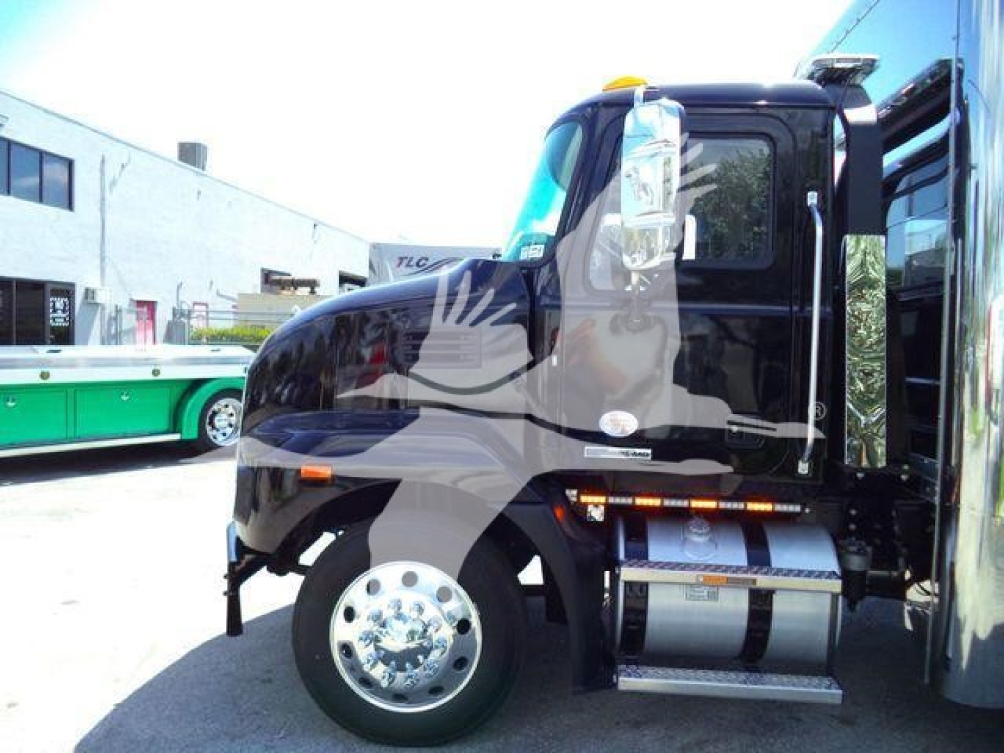 Mack MD6 truck front cab view showing black exterior, chrome front wheel, fuel tanks, and side mirrors.