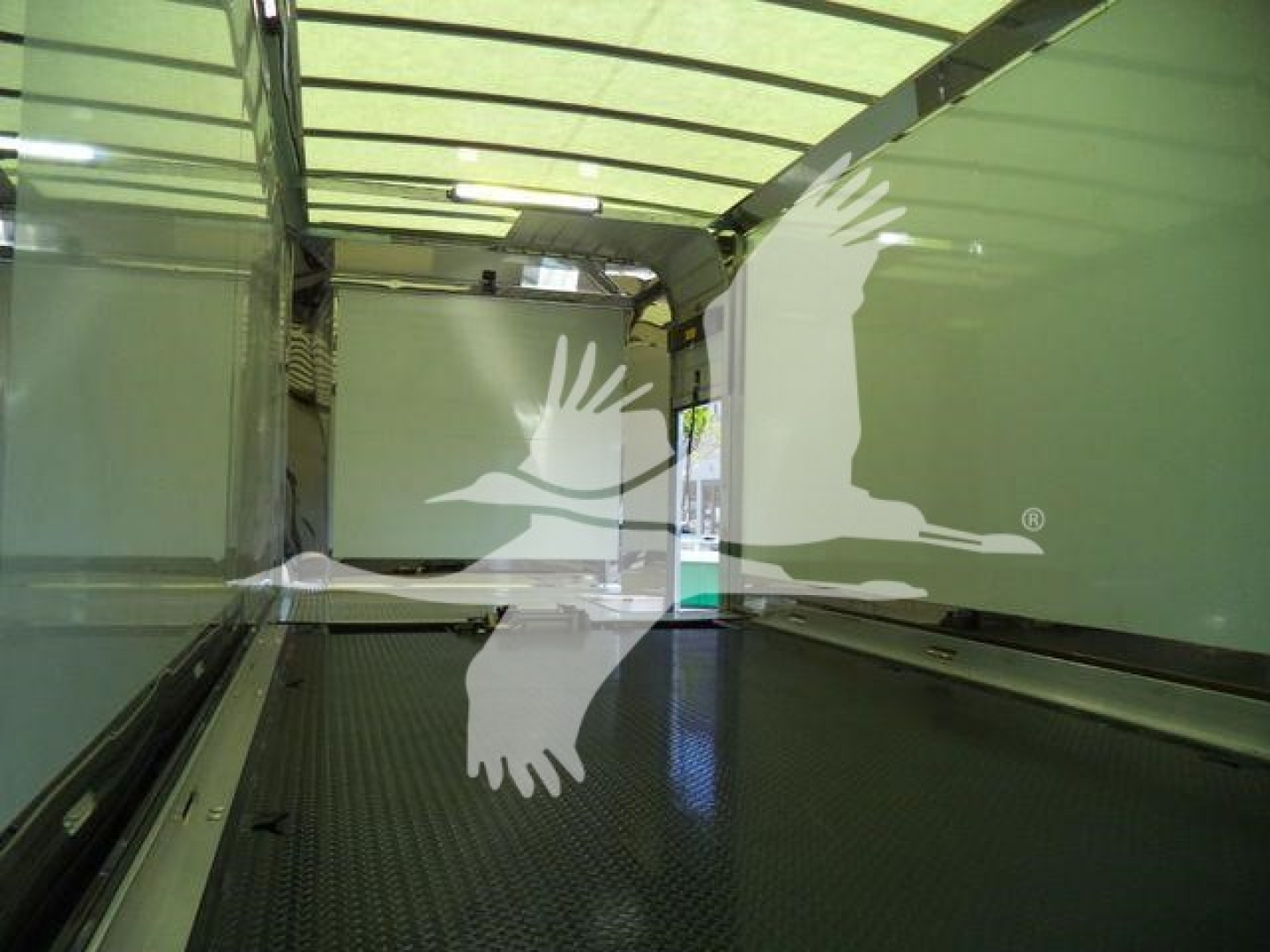 Mack MD6 rollback truck cargo area interior with green walls and diamond-plate floor, empty with overhead lighting.