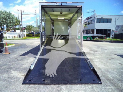 Rear view of a new Mack MD6 rollback truck with an open lowered ramp, showing a clean cargo area and black non-slip ramp surface.