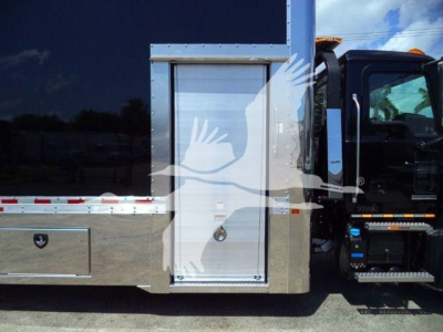 Truck side showing utility compartment door with polished metal panel and steps, part of a Mack MD6 rollback trucks chassis.