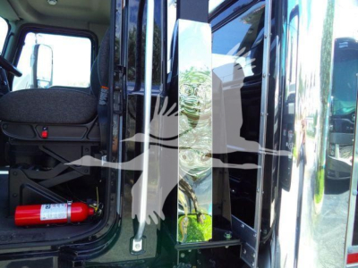 Truck cab interior with open door showing seat and red fire extinguisher on floor.
