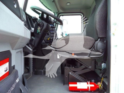 Cab interior of a 2026 Mack MD6 side-view showing steering wheel, dashboard, and operator seat with a fire extinguisher mounted near the floor.